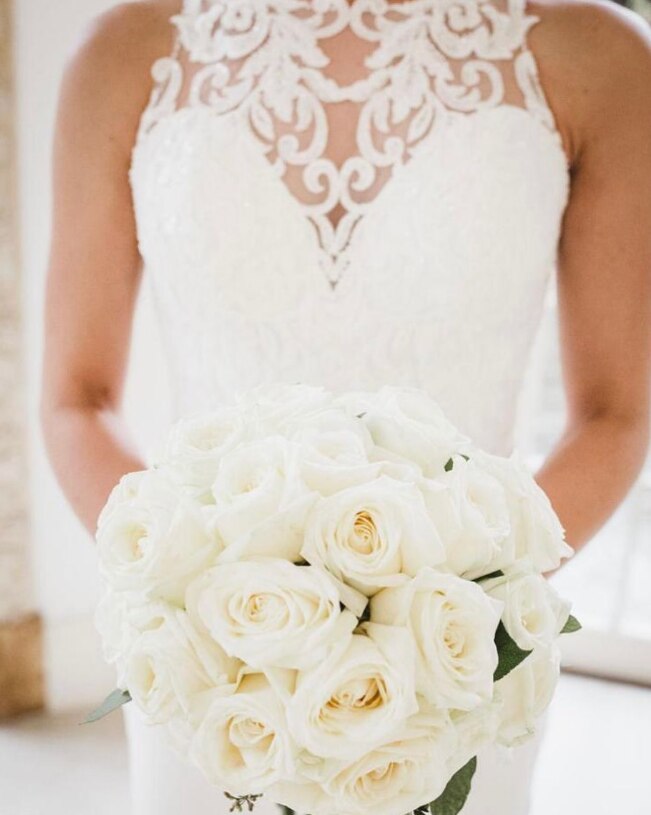The bride holding a stunning bridal bouquet made up of beautiful, large headed white roses